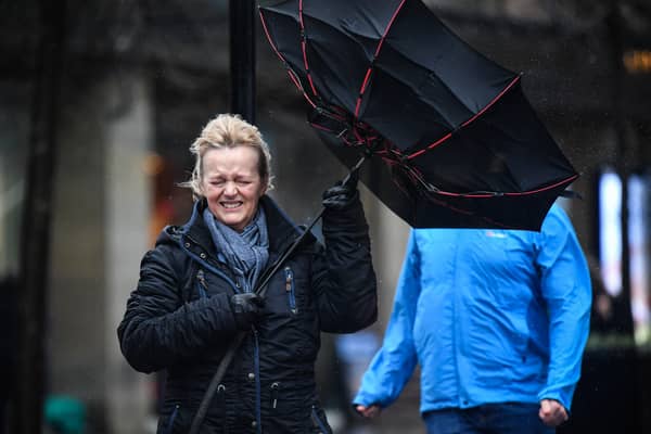 A woman battles to keep control of her umbrella as she walks through a rain shower in Glasgow.