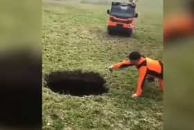 Hiker points to a giant sinkhole estimated to be around 20m deep