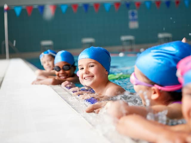 Portrait Of Children In Water At Edge Of Pool Waiting For Swimming Lesson