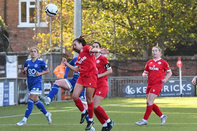 Defender Ella Terry wins a header, watched on by Skipper Sophia Wickenden and Ruby Melis.