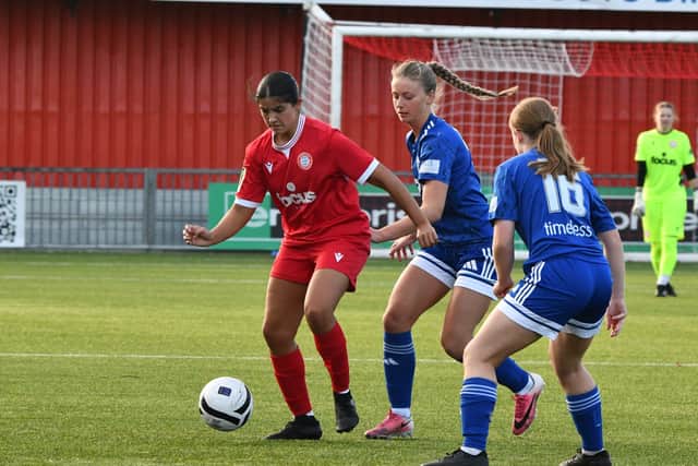 Midfielder Neve McEvaddy holds off a pair of blue shirts.