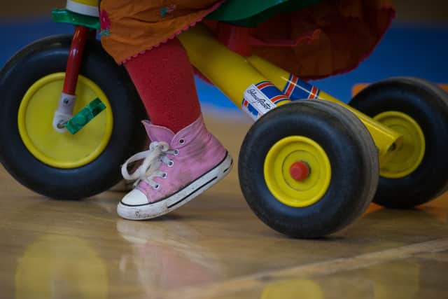  A toddler rides a trike.