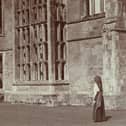 Stereoscopic view showing a woman standing in front of the ruins of Cowdray House. 