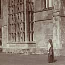 Stereoscopic view showing a woman standing in front of the ruins of Cowdray House. 