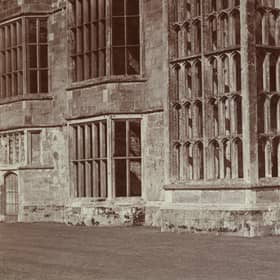 Stereoscopic view showing a woman standing in front of the ruins of Cowdray House. 