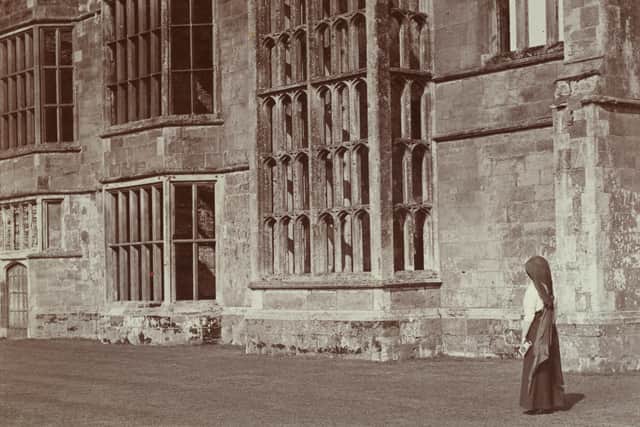 Stereoscopic view showing a woman standing in front of the ruins of Cowdray House. 