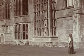 Stereoscopic view showing a woman standing in front of the ruins of Cowdray House. 