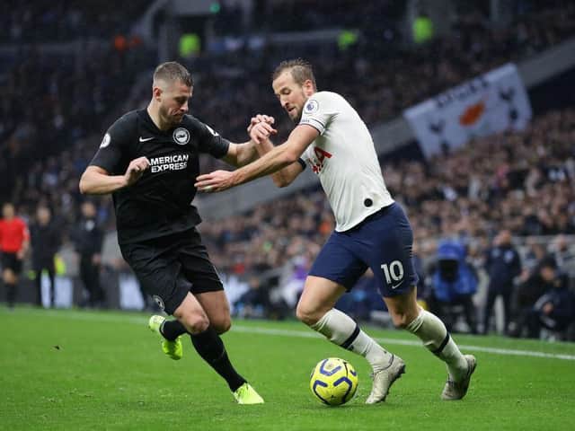 Brighton and Hove Albion defender Adam Webster tussles for possession with Harry Kane