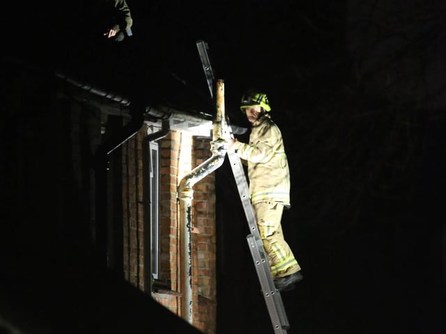 A firefighter scales the building
