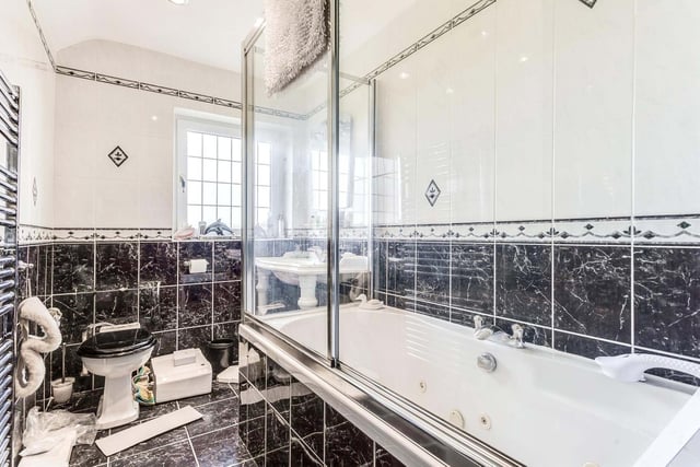 This monochrome bathroom includes a large bath with shower.