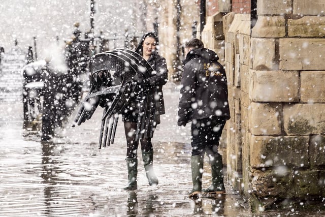Pub staff move chairs through flood water in heavy snow in York city centre