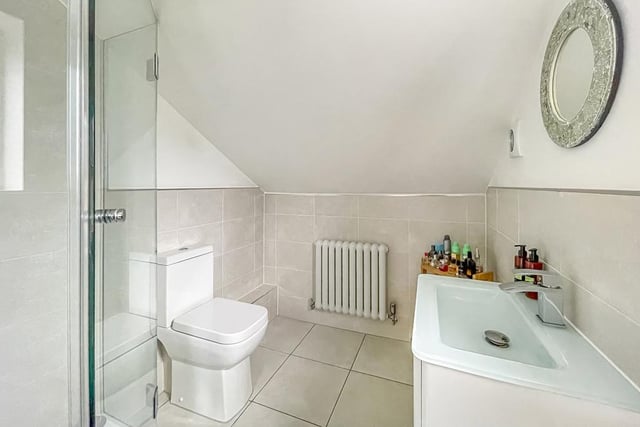 A white suite and shower cubicle in half-tiled bathroom