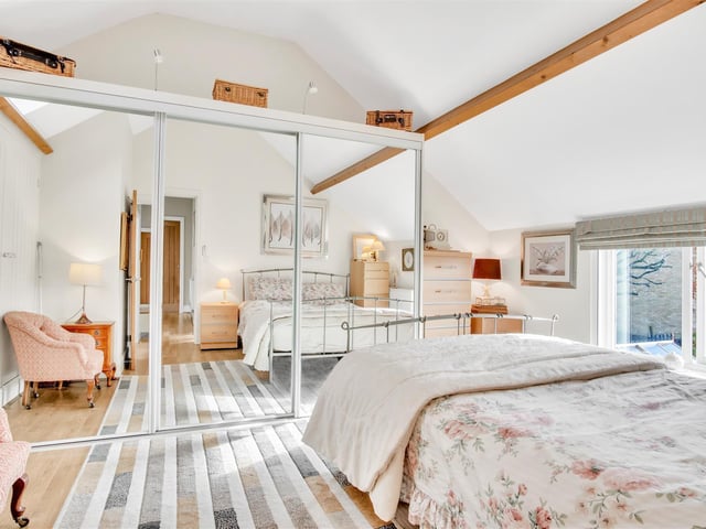 Light and furnished bedroom space with a beam to the ceiling.
