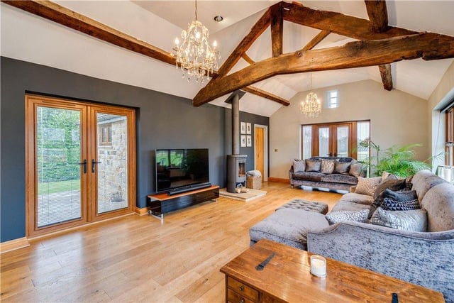 The impressive sitting room has exposed beams to vaulted ceilings, solid oak flooring and a contemporary multi fuel stove.