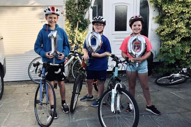 Samuel Ludlow and twins Ben and Emma Ludlow celebrate completing 100 miles on their Bike Ride for NHS challenge