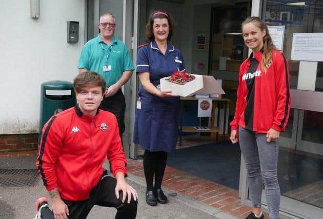 Lewes FC players Teddy Bloor and Katie Rood presenting the cake to nurse manager Nicky Axtell at Lewes Victoria Hospital