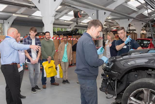Potential apprentices and their families and sponsors are shown a cover being be prepared for repair in the workshop