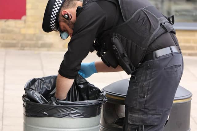 A police officer searches a bin in Gales Drive. Picture by Eddie Mitchell