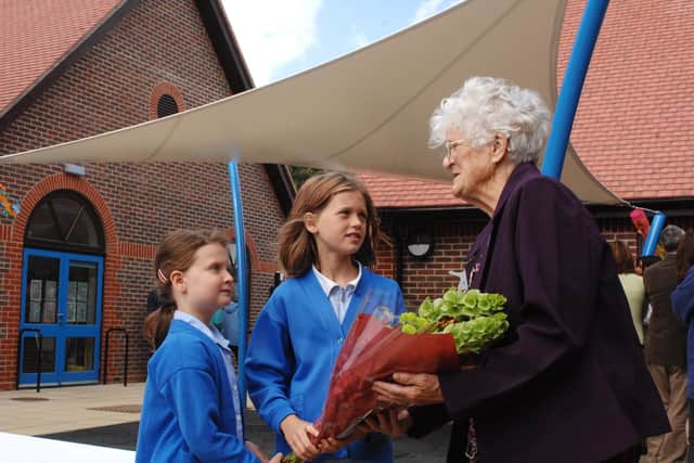 Former Fittleworth School pupil Irene Hawkins accepts a bouquet of flowers from pupils Lily Palmer, eight, and Ella Heaune, 11, at the opening of their school's new classrooms in July 2010. Picture: Louise Adams C101104-1