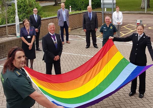 Members of various organisations outside Lewes' County Hall with the rainbow flag