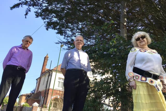 A Littlehampton priest has been without internet and a phone connection for weeks due to a damaged line. Pictured left to right: Paul Peppard, Father Carl Davies, Cate Peppard, in front of the telegraph pole that was damaged by tree overgrowth
