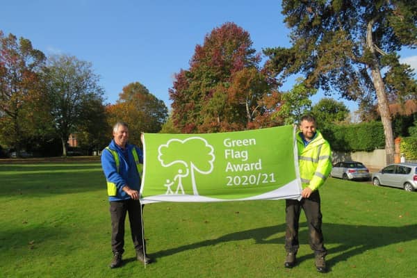 Head grounds man Andy Stempt and grounds staff member Samual Russell, proudly hold the Green Flag Award for 2020/2021 over Muster Green in Haywards Heath. Picture: Haywards Heath Town Council