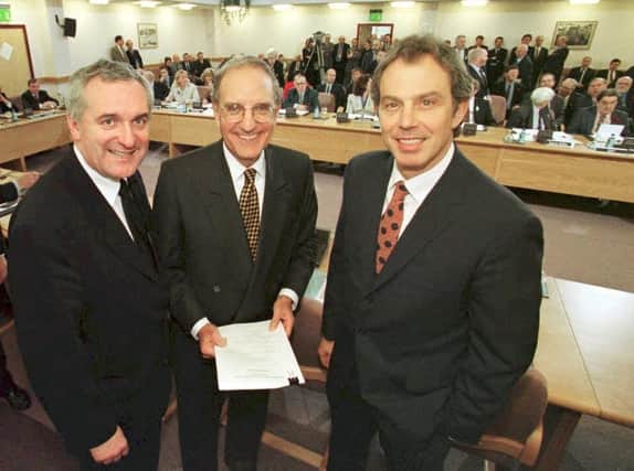 File picture of British Prime Minister Tony Blair (R), US Senator George Mitchell (C) and Irish Prime Minister Bertie Ahern (L) smiling on April 10, 1998, after they signed an historic agreement for peace in Northern Ireland, ending a 30-year conflict. (DAN CHUNG/AFP via Getty Images)