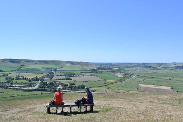Friends enjoy the view from the top of Mount Caburn, East Sussex (Photo by Glyn KIRK / AFP) (Photo by GLYN KIRK/AFP via Getty Images)