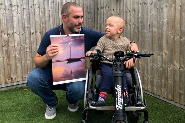 Jamie Fielding with his 2021 calendar and son Charlie Fielding with the Triride, funded by last year's calendar