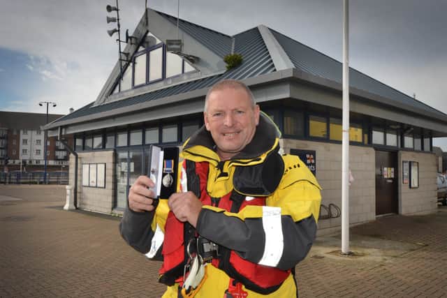 Coxswain Mark Sawyer holding his award outside Eastbourne Lifebaot Station. SUS-201020-152557001
