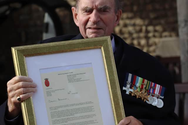 Captain Duncan Knight holds a framed letter from the First Sea Lord. Photo: Royal Navy