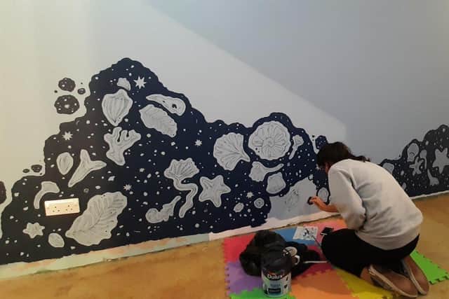 artist Ellie Fryer painting murals on the centre's walls SUS-200211-110711001