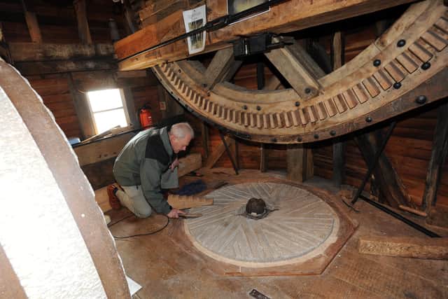 Long-standing volunteer Peter Casebow with the mill stone. Picture: Stephen Goodger W07643H12
