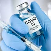 Healthcare cure concept with a hand in blue medical gloves holding Coronavirus, Covid 19 virus, vaccine vial. Picture: Adobe Stock YPN-201117-122910062