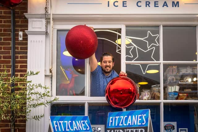 Jamie Cashman, manager of Fitzcane's cafe on North Street, Midhurst with two of the giant baubles that the traders of the town will be hanging outside their shops this Christmas. Photo: Christopher Ison