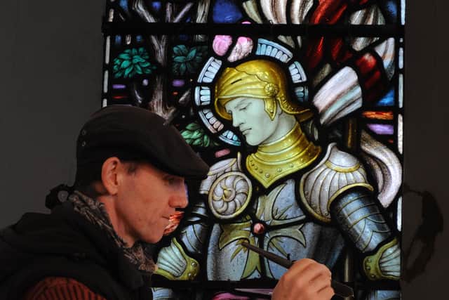 Restorer Vincent Groves applying the finishing touches to St George, one of six stained glass panels to be restored ten years ago Picture: Louise Adams C110248-1