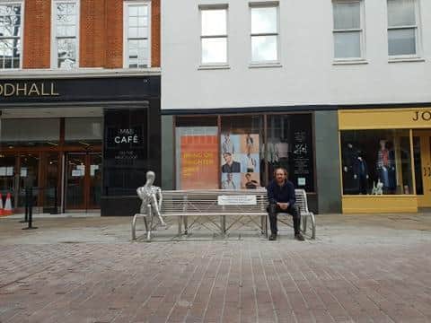 John Gillespie sitting on his sculpture in East Street