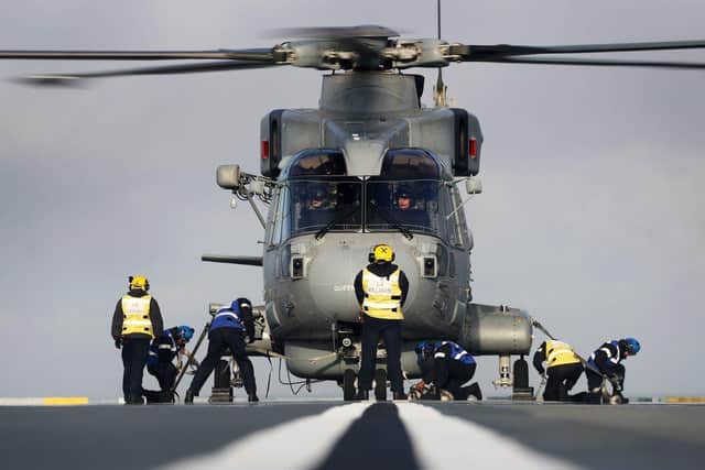 Aircraft handlers lash down a Merlin Mk2 helicopter on HMS Queen Elizabeth.  Picture: Royal Navy