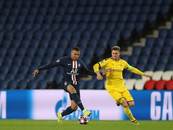 Kylian Mbappe of Paris Saint-Germain is challenged by Lukasz Piszczek of Borussia Dortmund during the Champions League round of 16 second leg match. The match is played behind closed doors as a precaution against the spread of COVID-19