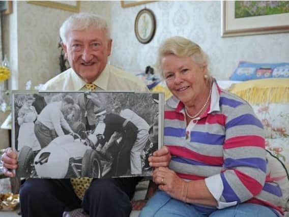 Jim and Annie Strudwick with a picture of them both when they were first on the scene at Goodwood, when Sir Stirling Moss had his accident in 1962. They are pictured in 2014, when they had both retired from the NHS after a total of more than 100 years Picture: Sarah Standing (141147-1529)
