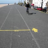 A cyclist beside social distancing markers on Worthing seafront
