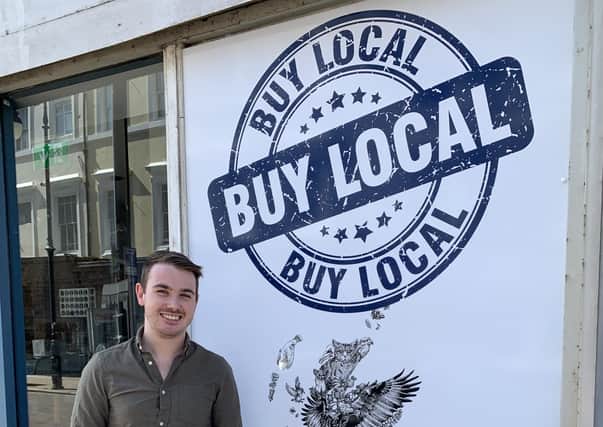 Artist Sam Johnson with his ‘Buy local’ mural in Robertson Street, next to the Bullet Cafe