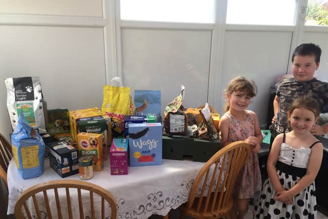 Catherine and Victoria Glynn with Ben Ellis and some of the cat and dog food they collected for donation to Mount Noddy