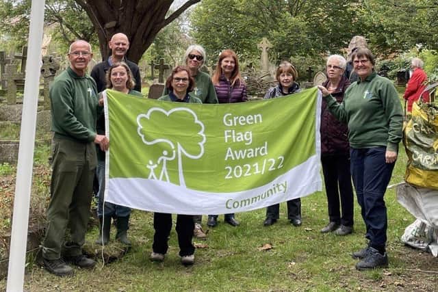 Volunteers raise the Green Flag Community Award at Heene Cemetery
