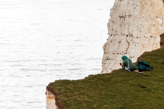 A person was seen looking over the edge of Beachy Head as they took a picture at the cliffs. (Picture from Tyrone Campbell/SWNS) SUS-211027-130746001