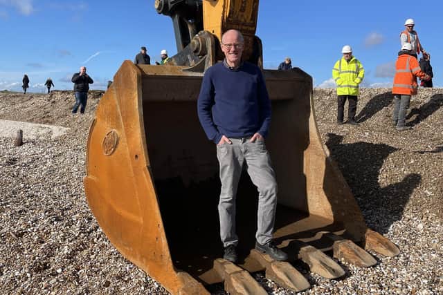 Nick Gibb standing in the ‘bucket’ of the 50 tonne excavator.as work starts fo cut a channel through Pagham Spit