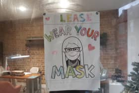 A drawing making people aware that mask wearing is mandatory is hanging up in the door of The Salon in Beach Road