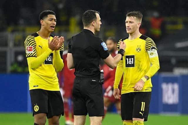 Midfielder Jude Bellingham and Dortmund's German forward Marco Reus discuss with referee Felix Zwayer