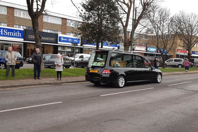 The funeral procession passes through The Street as people stand to pay their respects to Mary Taylor