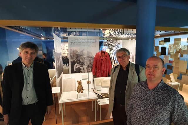 Tim (left) with his brother Stephen (back right) and cousin Tobias (front right) by the display case about their family (the Neumeyers) – one of three cases in the new Holocaust Galleries that feature their family.